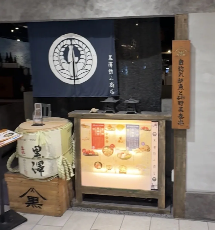黒澤惣三商店の入口。のれんと酒樽、メニューの看板